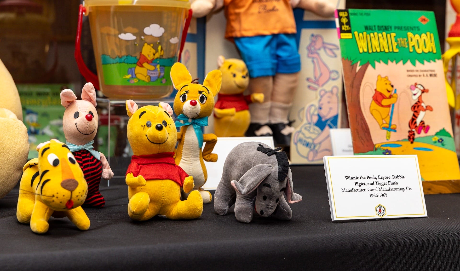 Retail display of Winnie the Pooh 100th anniversary collectibles in a modern gift shop setting